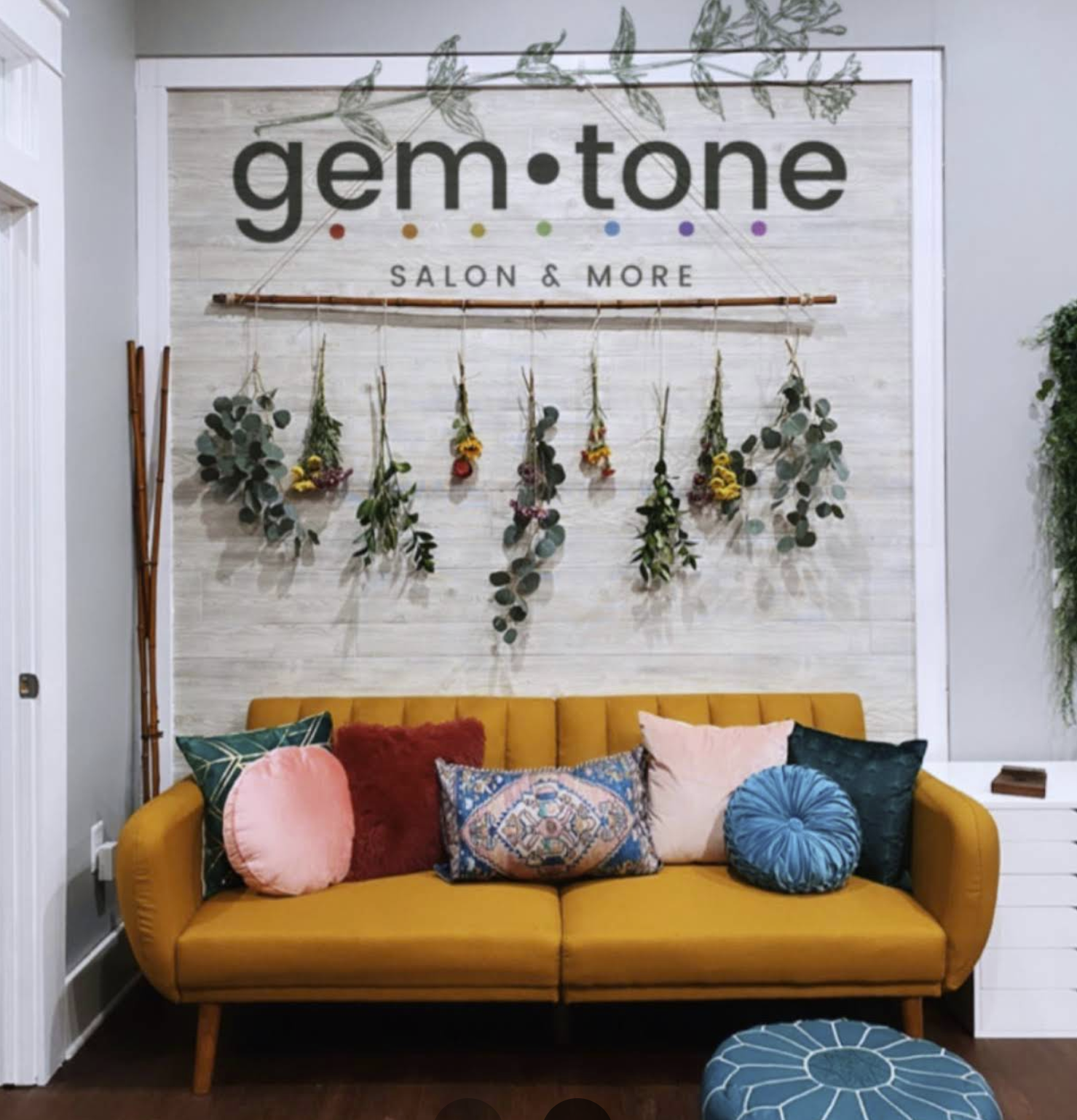 gem·tone salon interior — the mustard sofa and floral wall